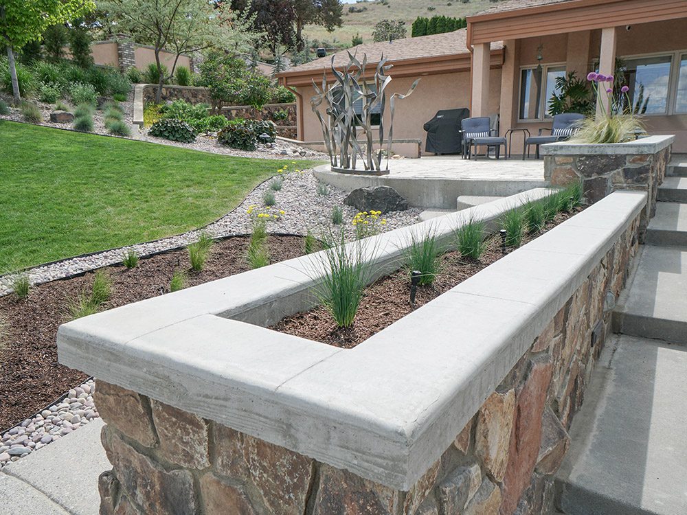 stone planter surrounded by stone and bark landscaping